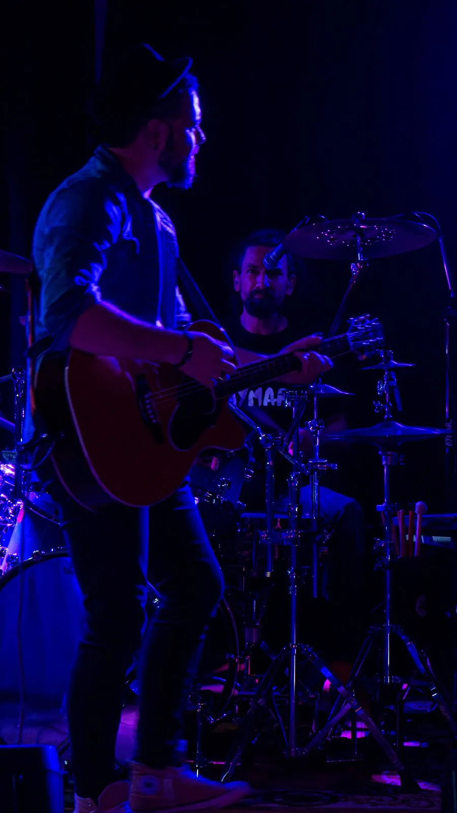 Le chanteur d'Aymar à la guitare acoustique, batterie en arrière-plan